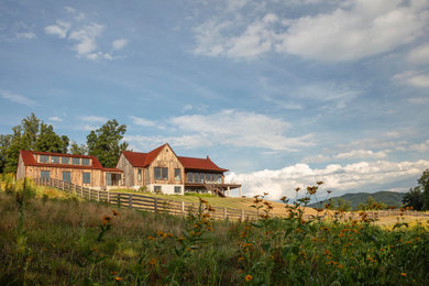 Example of a huge brown three-story wood and board and batten exterior home design in Other with a metal roof and a red roof
