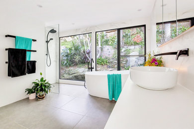 Design ideas for a large beach style master bathroom in Sydney with raised-panel cabinets, white cabinets, a freestanding tub, an open shower, a one-piece toilet, black and white tile, ceramic tile, white walls, ceramic floors, a vessel sink, solid surface benchtops, grey floor, an open shower and white benchtops.