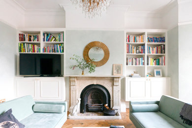 ロンドンにある高級な広いトラディショナルスタイルのおしゃれなリビング (緑の壁、標準型暖炉、石材の暖炉まわり、埋込式メディアウォール、茶色い床) の写真