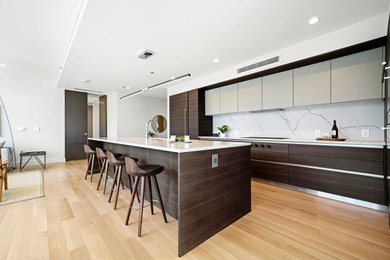 Inspiration for a contemporary l-shaped medium tone wood floor and brown floor kitchen remodel in Chicago with flat-panel cabinets, an undermount sink, dark wood cabinets, white backsplash, paneled appliances, an island and white countertops