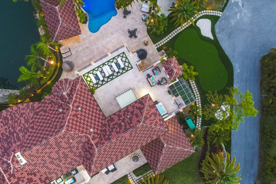 Example of a huge classic side yard stone patio design in Miami with a fire pit and a pergola