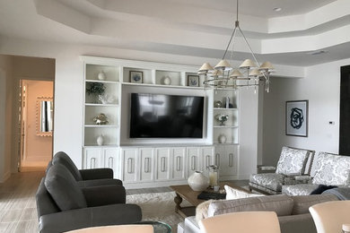 Photo of a mid-sized traditional enclosed family room in New York with white walls, porcelain floors, no fireplace, a wall-mounted tv and grey floor.