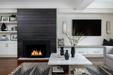 Large transitional open concept medium tone wood floor and brown floor living room photo in Toronto with white walls, a standard fireplace, a wood fireplace surround and a wall-mounted tv