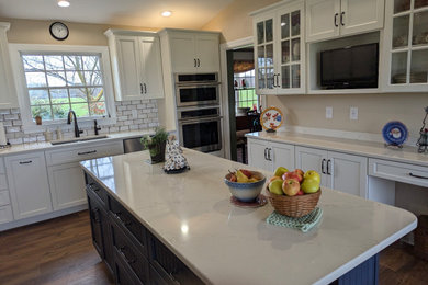 Eat-in kitchen - mid-sized traditional u-shaped brown floor eat-in kitchen idea in Other with a single-bowl sink, shaker cabinets, white cabinets, quartzite countertops, white backsplash, subway tile backsplash, stainless steel appliances, an island and white countertops