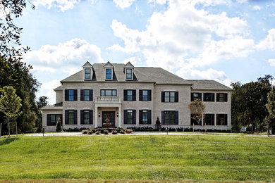 Example of a huge classic white three-story brick house exterior design in DC Metro with a hip roof and a shingle roof
