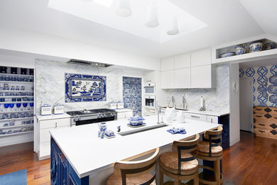 Inspiration for a large eclectic l-shaped medium tone wood floor and brown floor open concept kitchen remodel in Baltimore with an undermount sink, flat-panel cabinets, white cabinets, quartz countertops, blue backsplash, marble backsplash, stainless steel appliances and an island