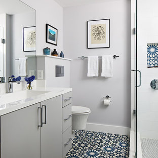 Corner shower - mid-sized contemporary 3/4 white tile blue floor corner shower idea in DC Metro with flat-panel cabinets, gray cabinets, a wall-mount toilet, gray walls, a hinged shower door, white countertops and an integrated sink