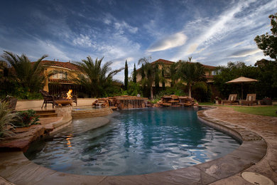 Modelo de piscina con fuente exótica grande en patio trasero con suelo de hormigón estampado