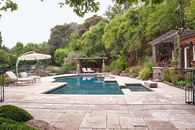 This is an example of a large arts and crafts backyard custom-shaped lap pool in San Francisco with a hot tub and concrete pavers.