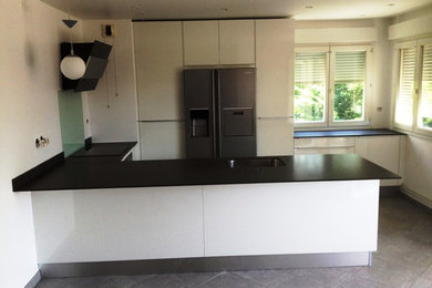 Large contemporary u-shaped kitchen/diner in Other with an integrated sink, beaded cabinets, white cabinets, granite worktops, black splashback, stone slab splashback, stainless steel appliances, ceramic flooring and a breakfast bar.