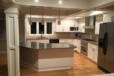 Inspiration for a mid-sized transitional u-shaped light wood floor open concept kitchen remodel in Cleveland with a double-bowl sink, shaker cabinets, white cabinets, granite countertops, beige backsplash, ceramic backsplash, stainless steel appliances and a peninsula
