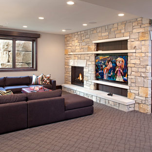 Photo of a traditional look-out basement in Minneapolis with grey walls, carpet, a standard fireplace, a stone fireplace surround and grey floors.