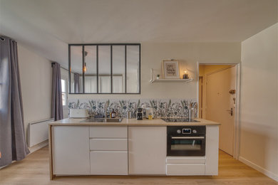 Cette image montre une petite cuisine ouverte linéaire et blanche et bois design avec un évier 1 bac, des portes de placard blanches, un plan de travail en stratifié, une crédence multicolore et un sol en vinyl.