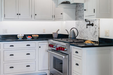 Eat-in kitchen - large country u-shaped slate floor and beige floor eat-in kitchen idea in Burlington with a farmhouse sink, recessed-panel cabinets, gray cabinets, granite countertops, black backsplash, ceramic backsplash, stainless steel appliances, an island and black countertops