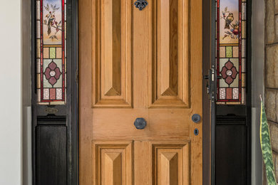 This is an example of a traditional front door in Adelaide with white walls, concrete floors, a single front door, a medium wood front door and black floor.