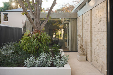 Inspiration for a small contemporary two-storey house exterior in Adelaide with stone veneer, a flat roof, a metal roof and a black roof.
