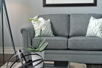 Inspiration for a mid-sized transitional dark wood floor and brown floor living room remodel in Toronto with a wall-mounted tv, gray walls, a standard fireplace and a wood fireplace surround