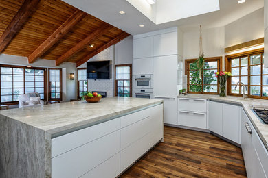 This is an example of a contemporary open plan kitchen in Dallas with flat-panel cabinets, white cabinets, quartzite benchtops, white appliances, medium hardwood floors and with island.