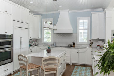 Example of a mid-sized transitional galley medium tone wood floor and brown floor eat-in kitchen design in Grand Rapids with an undermount sink, shaker cabinets, white cabinets, quartzite countertops, white backsplash, porcelain backsplash, paneled appliances and an island
