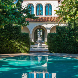 マイアミの巨大な円形地中海スタイルのおしゃれな競泳用プール (天然石敷き) の写真