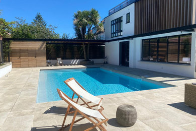 Medium sized modern back rectangular swimming pool in London with with pool landscaping and natural stone paving.