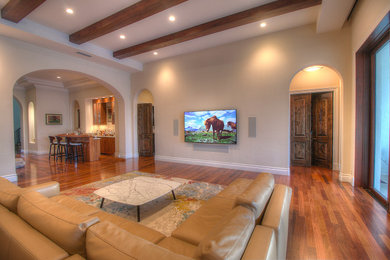 Living room - large mediterranean loft-style medium tone wood floor and brown floor living room idea in Miami with beige walls, no fireplace and a wall-mounted tv