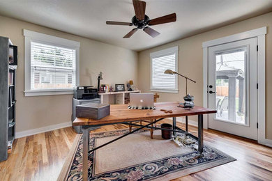 This is an example of a mid-sized transitional home office in Boise with beige walls, light hardwood floors and a freestanding desk.