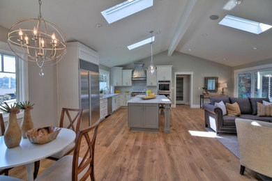 Open concept kitchen - transitional l-shaped light wood floor and brown floor open concept kitchen idea in San Francisco with an undermount sink, shaker cabinets, white cabinets, quartzite countertops, white backsplash, porcelain backsplash, stainless steel appliances and an island