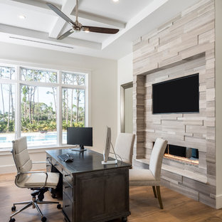 Foto på ett vintage arbetsrum, med mellanmörkt trägolv, en dubbelsidig öppen spis, en spiselkrans i trä, brunt golv, vita väggar och ett fristående skrivbord