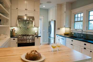 Eat-in kitchen - mid-sized craftsman u-shaped light wood floor eat-in kitchen idea in Portland with an undermount sink, shaker cabinets, white cabinets, wood countertops, glass tile backsplash, stainless steel appliances and a peninsula