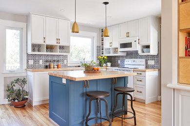 Inspiration for a small transitional l-shaped medium tone wood floor eat-in kitchen remodel in Ottawa with a drop-in sink, shaker cabinets, blue cabinets, wood countertops, blue backsplash, ceramic backsplash, white appliances and an island