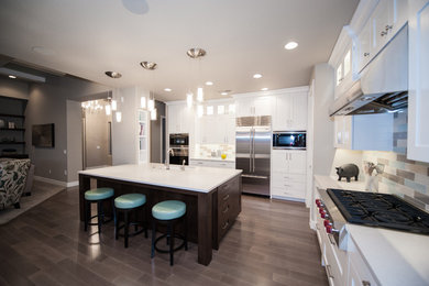 This is an example of a large contemporary l-shaped open plan kitchen in Salt Lake City with an undermount sink, shaker cabinets, white cabinets, soapstone benchtops, multi-coloured splashback, porcelain splashback, stainless steel appliances, dark hardwood floors, with island and brown floor.