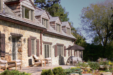 Large traditional beige two-story stone gable roof idea in Montreal