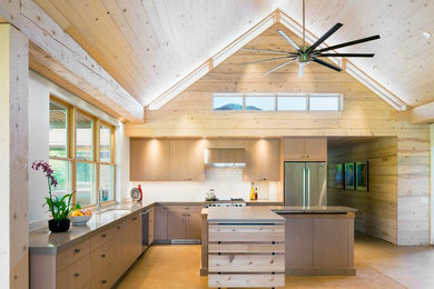 Kitchen - rustic l-shaped concrete floor kitchen idea in Denver with an undermount sink, flat-panel cabinets, light wood cabinets, white backsplash, subway tile backsplash, stainless steel appliances and an island