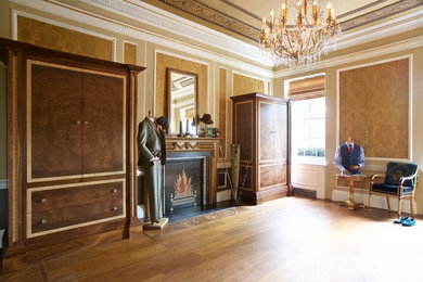 Photo of a traditional dressing room for men in London with flat-panel cabinets and dark wood cabinets.
