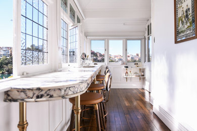 Mid-sized traditional l-shaped seated home bar in Sydney with an integrated sink, marble benchtops, dark hardwood floors and brown floor.