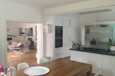 Offenes, Großes Modernes Esszimmer mit weißer Wandfarbe, Eckkamin, Kaminumrandung aus Backstein und braunem Boden in Düsseldorf