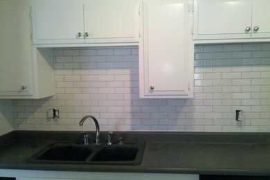 Enclosed kitchen - transitional l-shaped enclosed kitchen idea in Sacramento with a double-bowl sink, raised-panel cabinets, white cabinets, quartzite countertops, white backsplash, subway tile backsplash and stainless steel appliances