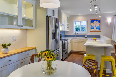 Inspiration for a small coastal u-shaped medium tone wood floor open concept kitchen remodel in San Francisco with an undermount sink, shaker cabinets, white cabinets, quartzite countertops, blue backsplash, stainless steel appliances, a peninsula and subway tile backsplash