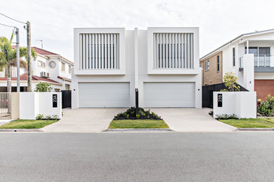 This is an example of a contemporary two-storey white duplex exterior in Gold Coast - Tweed with a flat roof.