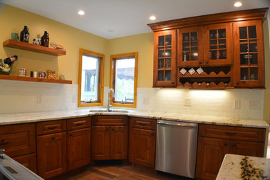 Mid-sized elegant u-shaped porcelain tile eat-in kitchen photo in Boston with white backsplash, stainless steel appliances, an undermount sink, glass-front cabinets, medium tone wood cabinets, subway tile backsplash, a peninsula and granite countertops