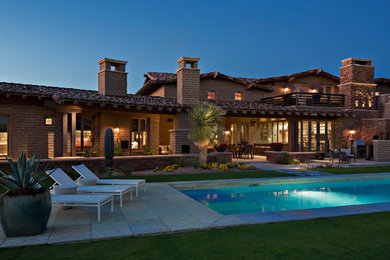 Design ideas for a large arts and crafts two-storey adobe beige exterior in Phoenix.