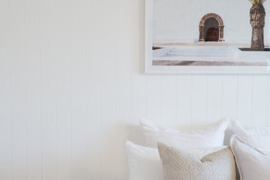 Design ideas for a mid-sized beach style guest bedroom in Sydney with white walls and light hardwood floors.