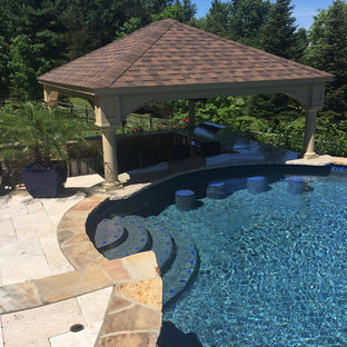 Example of a large mountain style backyard stone and custom-shaped pool house design in Philadelphia