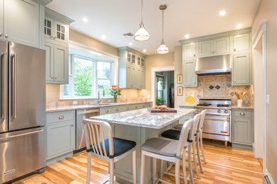 Mid-sized traditional u-shaped eat-in kitchen in Boston with stainless steel appliances, with island, brown floor, shaker cabinets and medium hardwood floors.