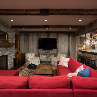 Modelo de sótano con ventanas de estilo de casa de campo, grande, con paredes marrones, suelo de cemento, chimenea tradicional, marco de chimenea de piedra y suelo marrón