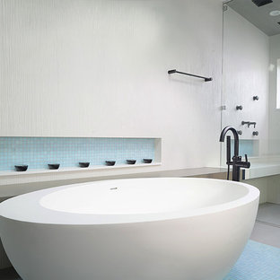 Ispirazione per una grande stanza da bagno padronale minimalista con ante di vetro, ante bianche, vasca freestanding, doccia a filo pavimento, bidè, piastrelle bianche, piastrelle in ceramica, pavimento in gres porcellanato, lavabo sottopiano, top in vetro riciclato, pavimento grigio e porta doccia a battente