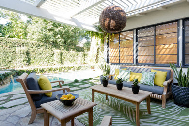 This is an example of an eclectic backyard patio in Los Angeles with natural stone pavers and a pergola.