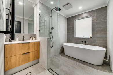 Large modern master bathroom in Perth with open cabinets, light wood cabinets, a freestanding tub, an open shower, multi-coloured tile, porcelain tile, multi-coloured walls, porcelain floors, an undermount sink, solid surface benchtops, beige floor, an open shower and white benchtops.