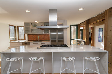 Photo of a large modern galley eat-in kitchen in Baltimore with an undermount sink, flat-panel cabinets, white cabinets, quartz benchtops, stainless steel appliances, medium hardwood floors, with island and white benchtop.